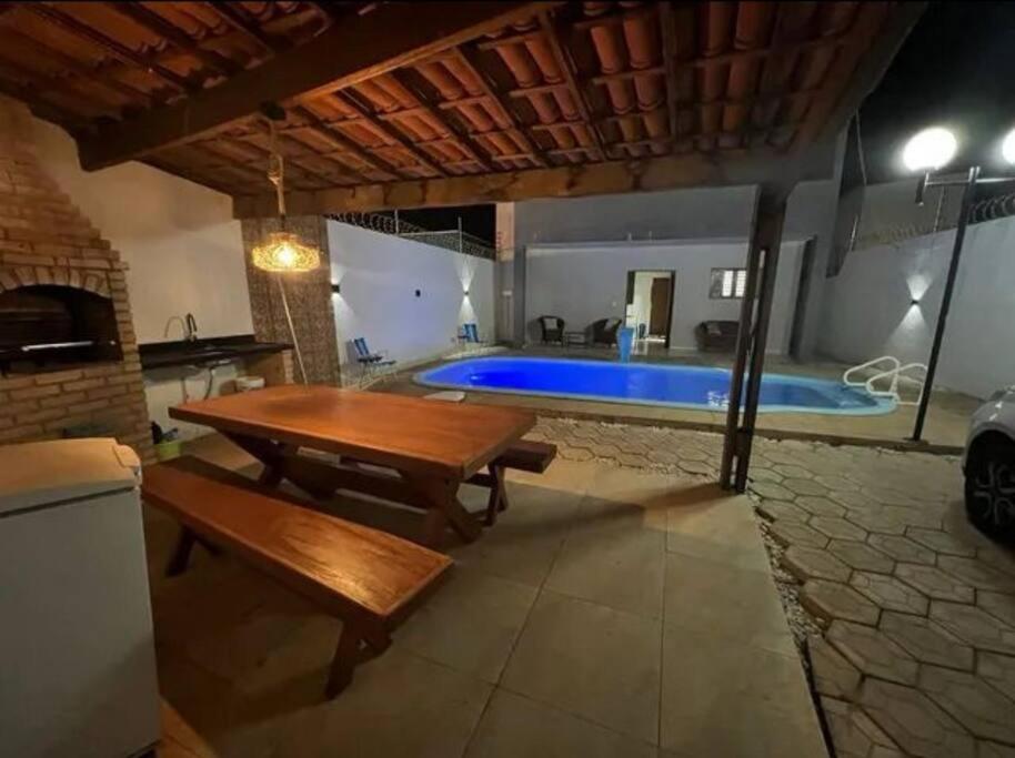 a patio with a table and a swimming pool at Linda casa com piscina in São Miguel do Gostoso