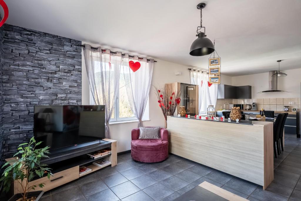 a living room with a counter and a tv and a kitchen at Gite au coin de la petite chapelle gitesdes2vallees in Cornimont