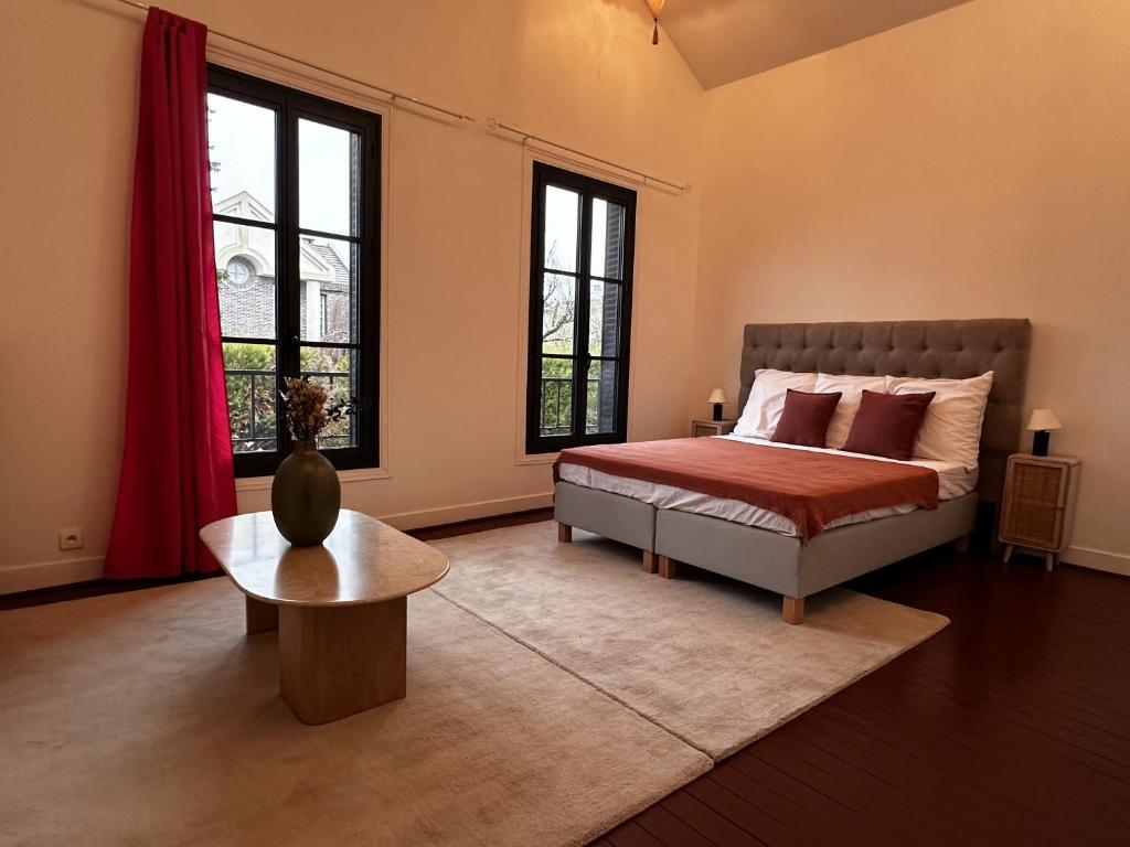 Schlafzimmer mit einem Bett, einem Tisch und Fenstern in der Unterkunft Villa avec jardin in Saint-Cloud