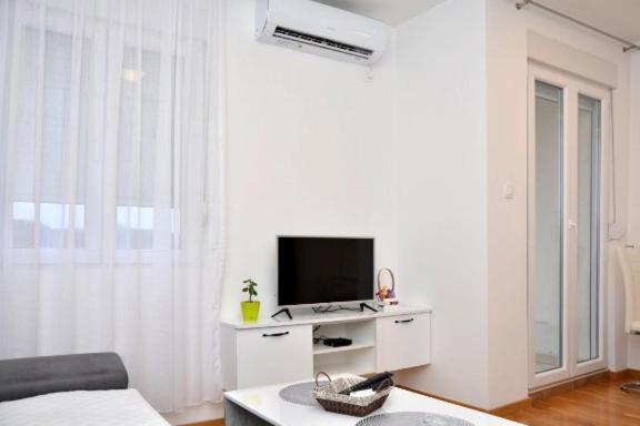 uma sala de estar branca com uma televisão e um sofá em Laki em Nikšić