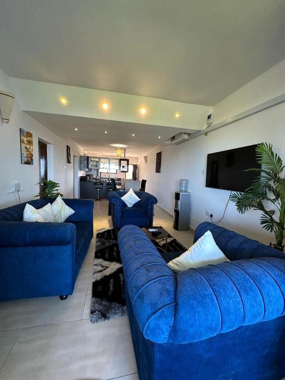 a living room with blue couches and a flat screen tv at Imani Front Beach Appartment in Diani Beach