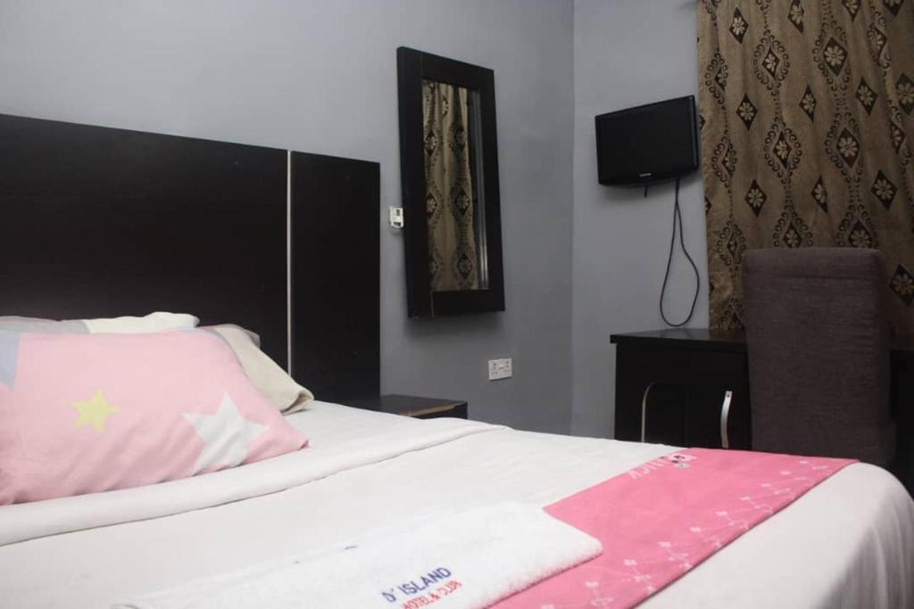 um quarto com uma cama com um cobertor rosa e branco em D'Island Hotel and Club em Lekki