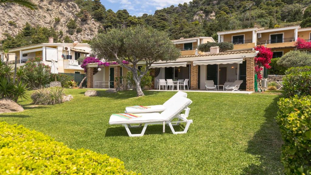 Una casa con dos sillones blancos en el césped. en Villa Sand and Sea, en Pelekas
