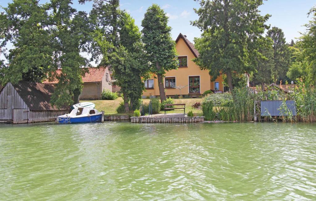 un bateau dans l'eau devant une maison dans l'établissement 1 Bedroom Beautiful Apartment In Feldberger Seenlandsch, à Amtshof