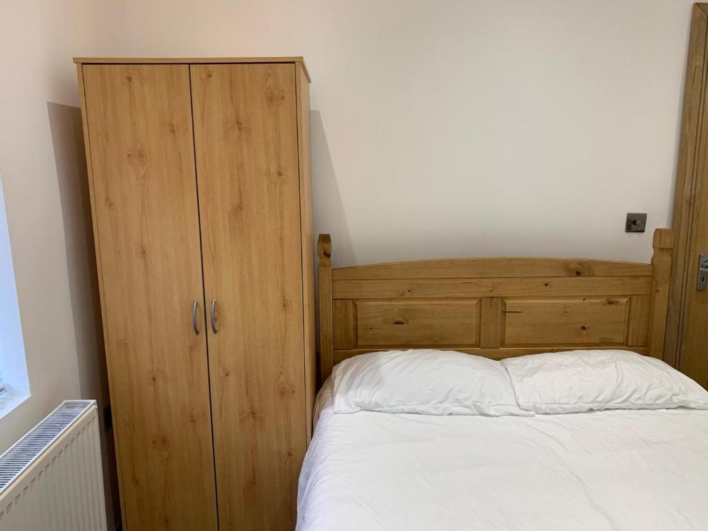 um quarto com uma cama e um armário de madeira em Private room, renovated with large size white desk In SE9 6PG em Londres