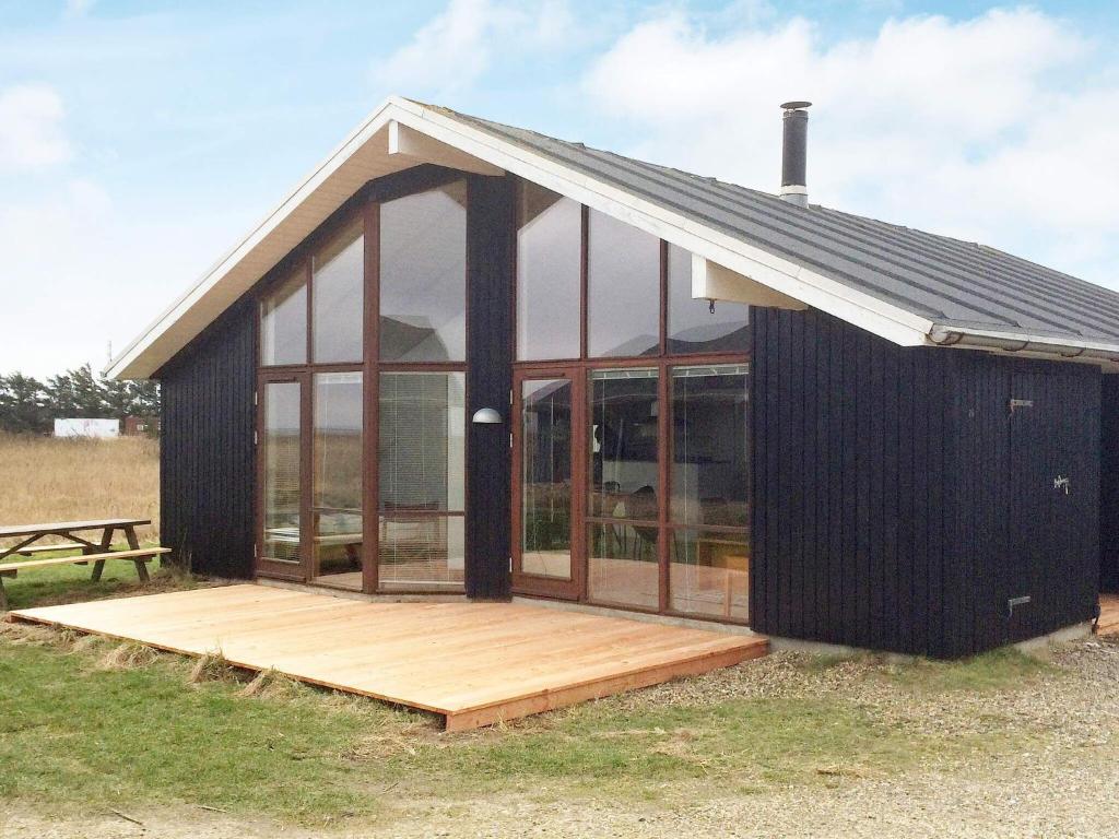 een zwart huis met glazen ramen en een houten terras bij 7 person holiday home in Ulfborg in Thorsminde