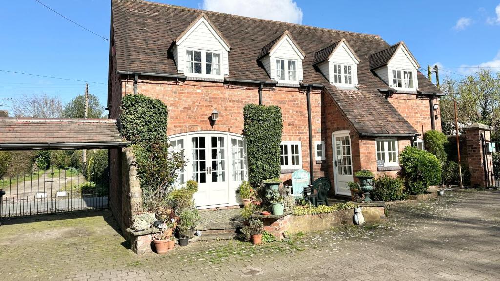 an old brick house with plants in front of it at Holly Cottage in Muxton