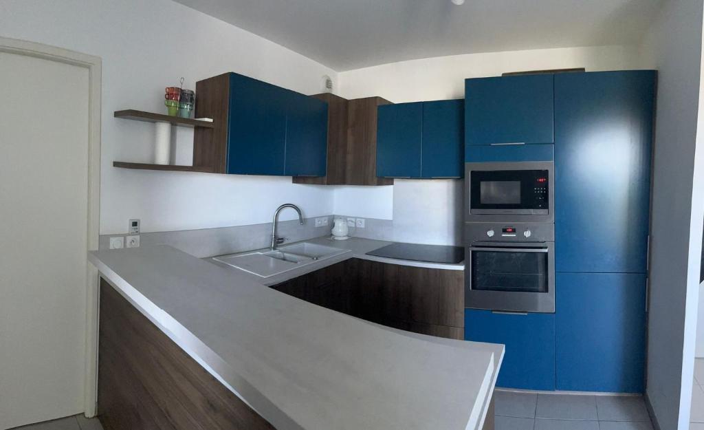 La cuisine est équipée de placards bleus, d'un évier et d'un four micro-ondes. dans l'établissement Appartement T2, à Montpellier