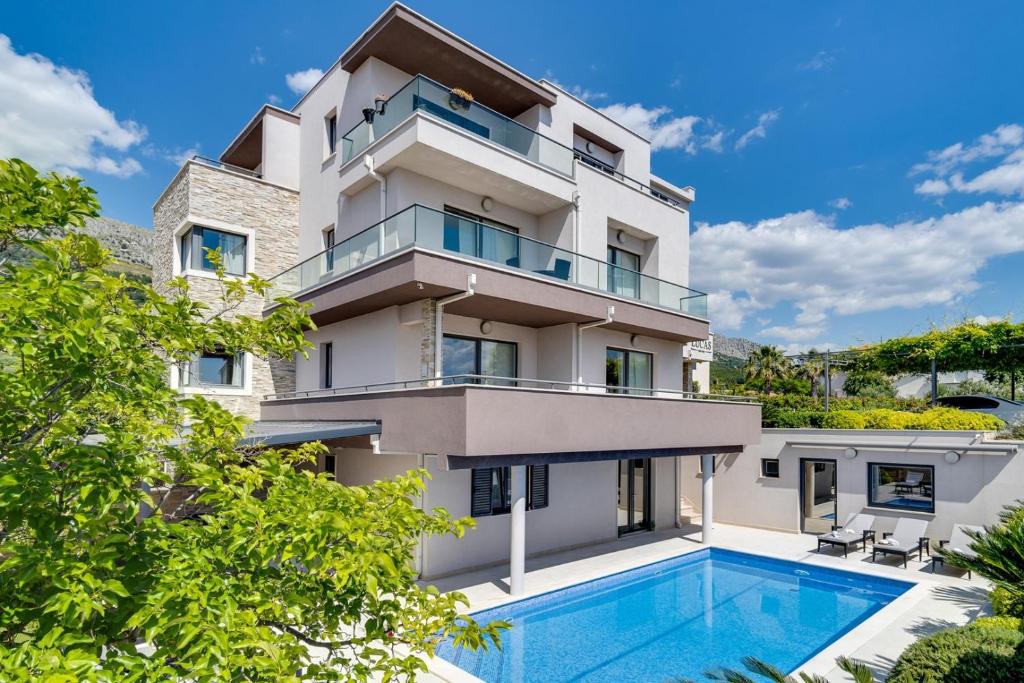 een appartementencomplex met een zwembad ervoor bij Luxury Villa Lucas with heated pool, whirlpool, sauna, 14 pax in Podstrana