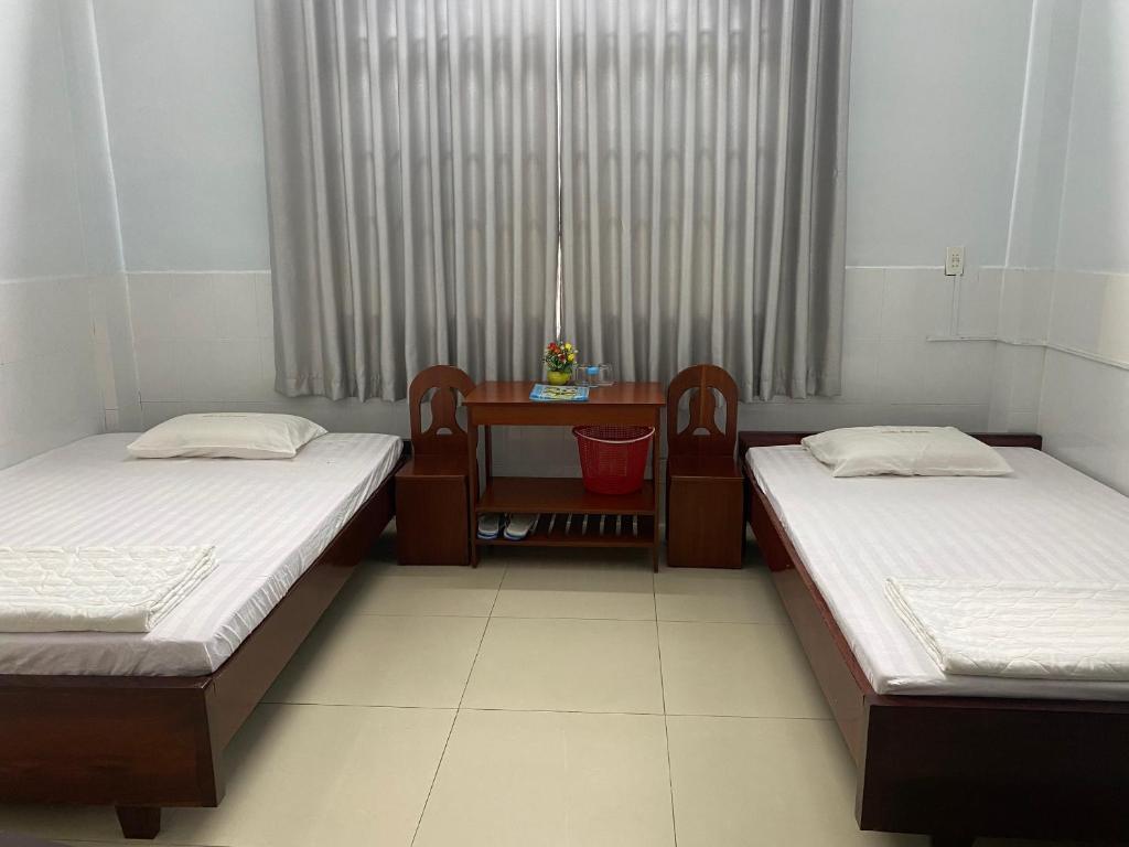a room with two beds and a desk and a table at Khách sạn Tường Minh in Cao Lãnh
