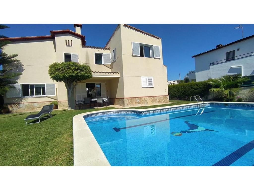 a large swimming pool in front of a house at Villa Tropical in Comarruga