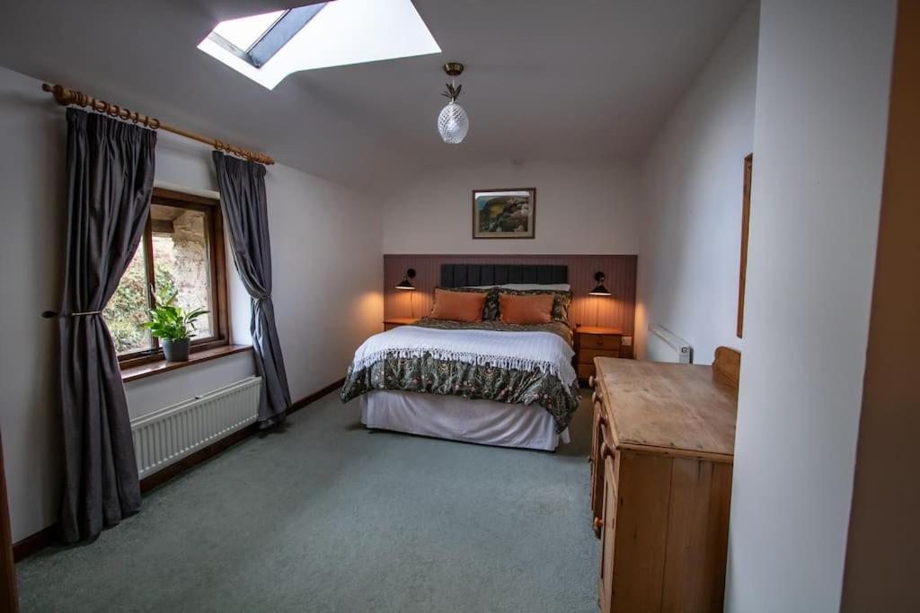 a bedroom with a bed and a window at The Wheelhouse at Hewish Mill in Bittadon