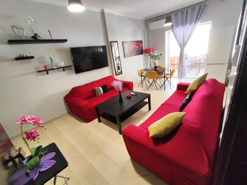 una sala de estar con 2 sofás rojos y una mesa. en Marlen House Chania, en La Canea