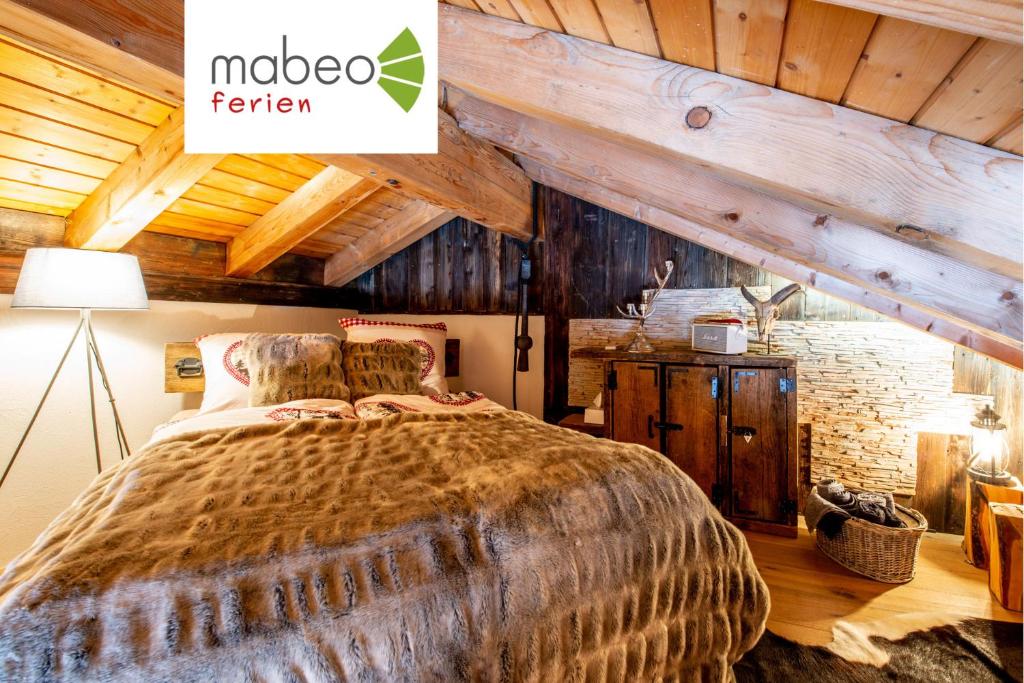 una camera con un grande letto in una stanza con soffitti in legno di Chalet Bijou a Blitzingen