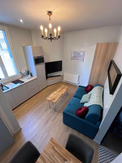 un salon avec un canapé bleu et une cuisine dans l'établissement Studio Gare, à Rouen