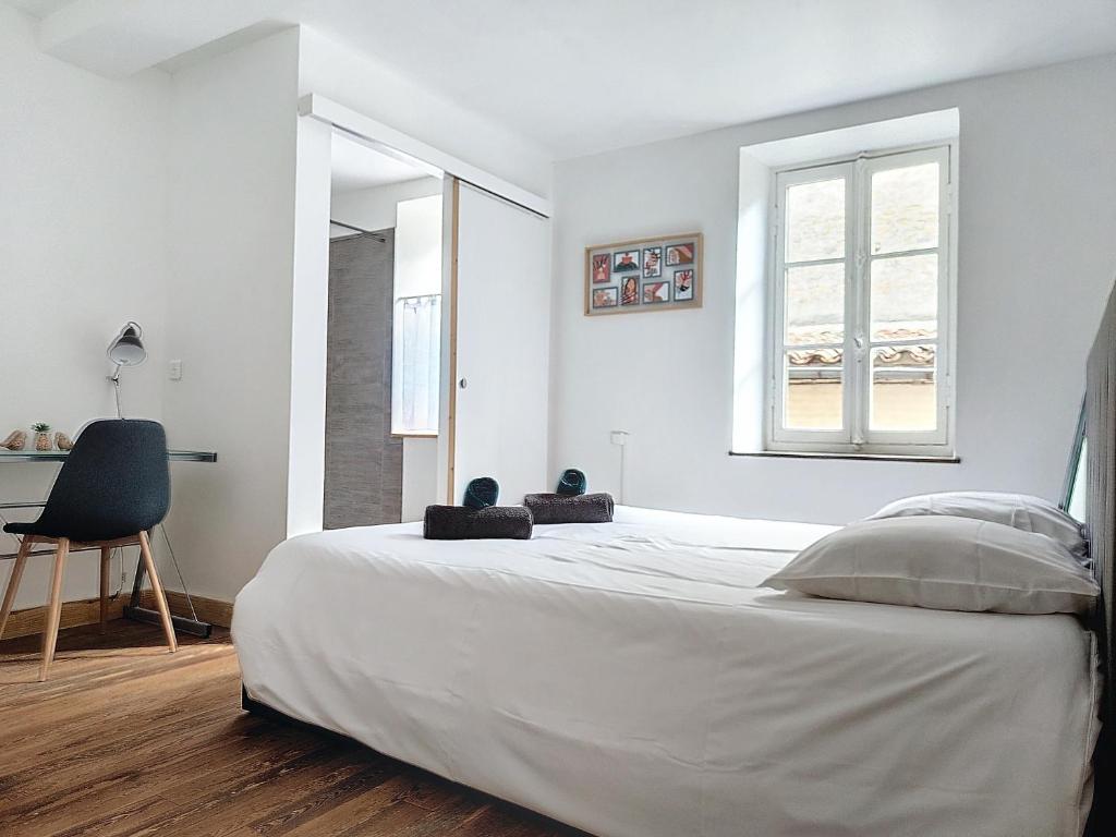 - une chambre blanche avec un grand lit et une fenêtre dans l'établissement Le Iéna, à Carcassonne