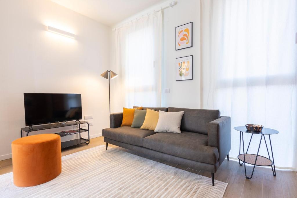 uma sala de estar com um sofá e uma televisão de ecrã plano em CaseOspitali - Glam Flat, nuovo trilocale di design zona Prada con box em Milão