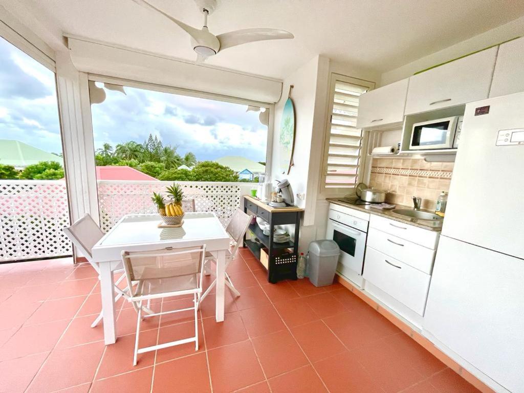 a kitchen with a white table and a white refrigerator at Résidence Anse des Rochers Guadeloupe Saint-François - quart de villa vue mer avec citerne et wifi privés in Saint-François