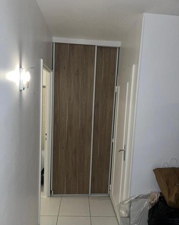 um corredor com uma porta de madeira num quarto em Belle chambre à louer em Sevran