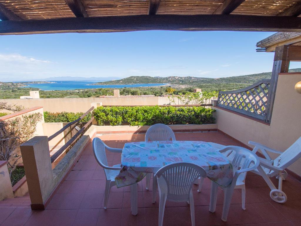 una mesa y sillas en un balcón con vistas al océano en Villetta Cala Petralana, en Porto Pollo