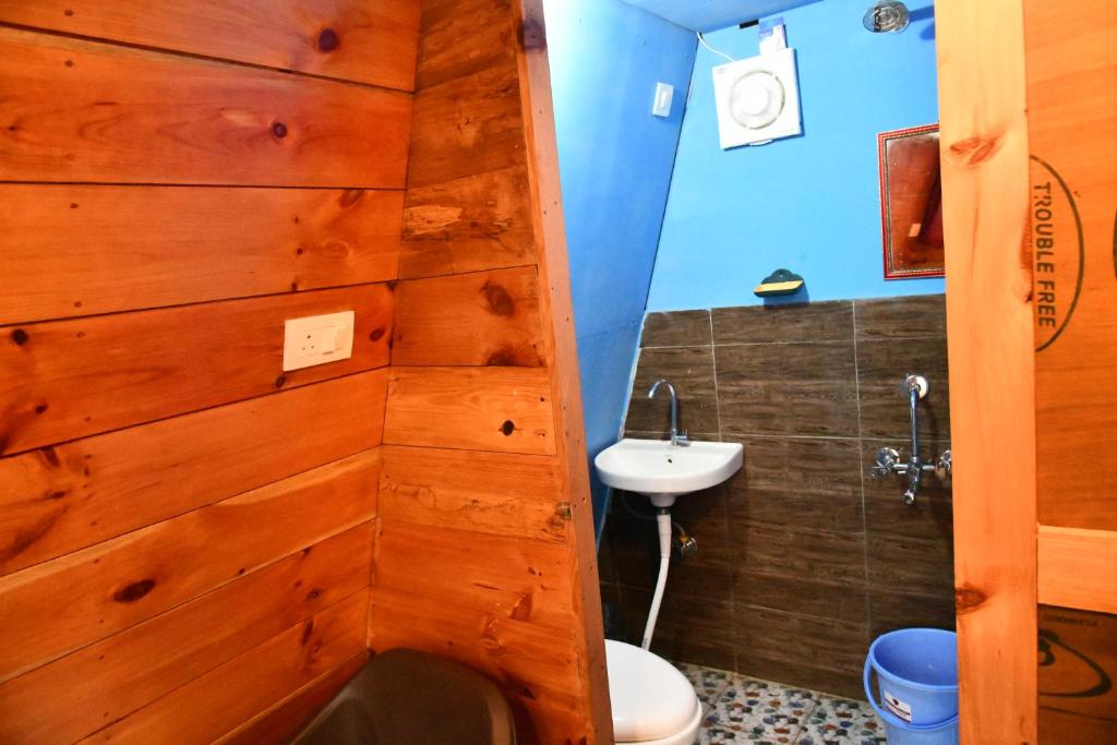 Hawk Camping & Cottages في ناينيتال: حمام بجدار خشبي ومرحاض ومغسلة