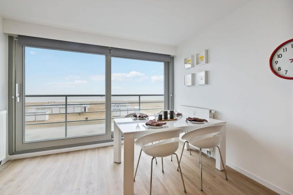 comedor con mesa y sillas y ventana grande en Apartment with frontal sea view in Knokke, en Knokke-Heist