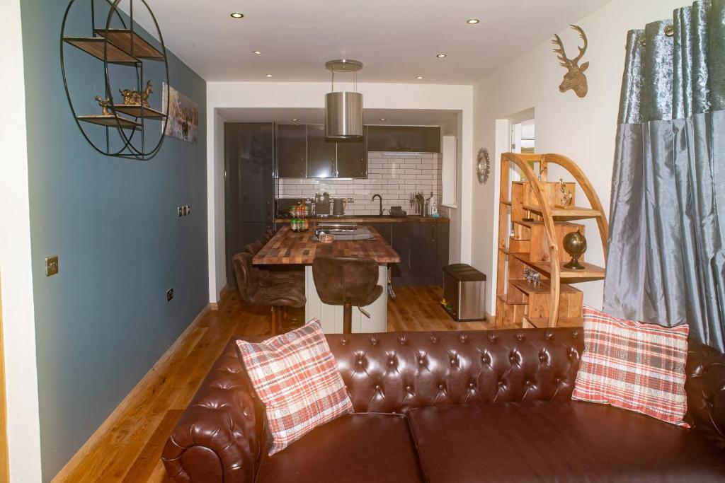 a living room with a brown leather couch and a kitchen at Luxury 3 Bedroom Cottage With Stunning Views Near Fairy Pools! in Carbost