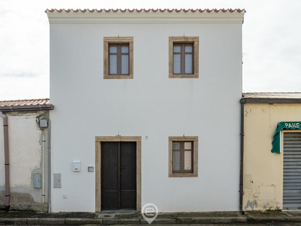 a white building with a black door and windows at Maria Grazia's Holiday Home in Massama