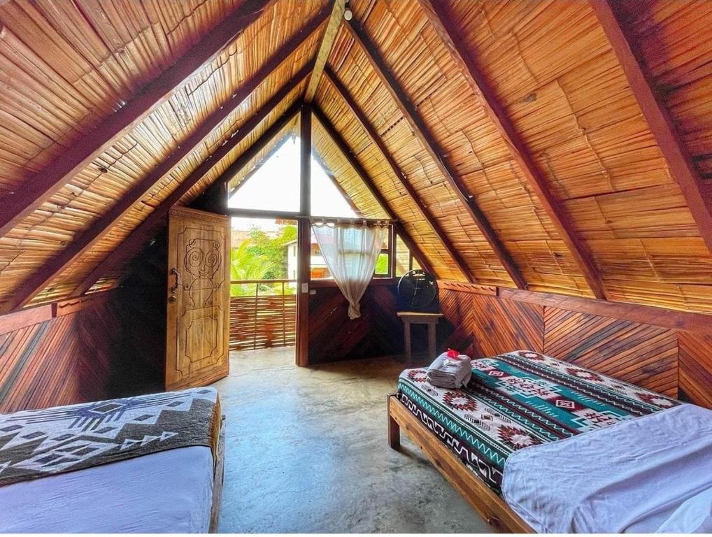 een kamer met 2 bedden en een groot raam bij Hotel Palma Coco in Ayampe