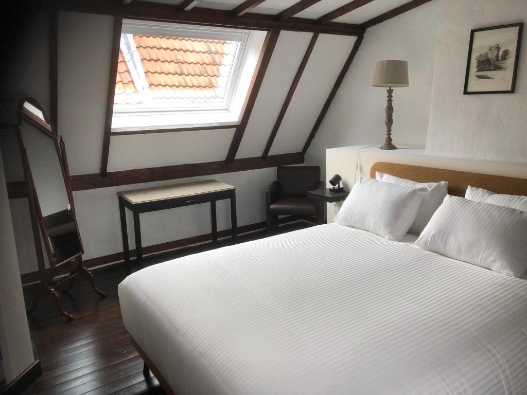 een slaapkamer met een wit bed en een raam bij De Pelgrim in Tongeren