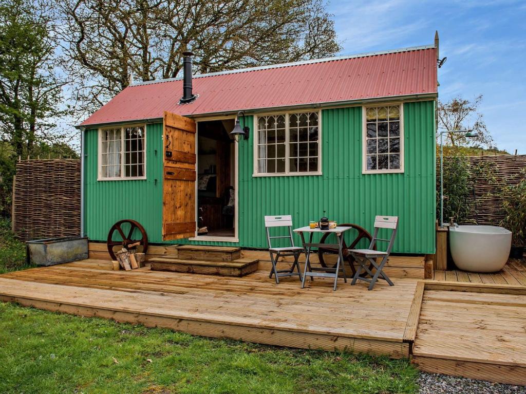 een groen huis met een tafel en stoelen op een terras bij 1 Bed in Poynings 90450 in Poynings