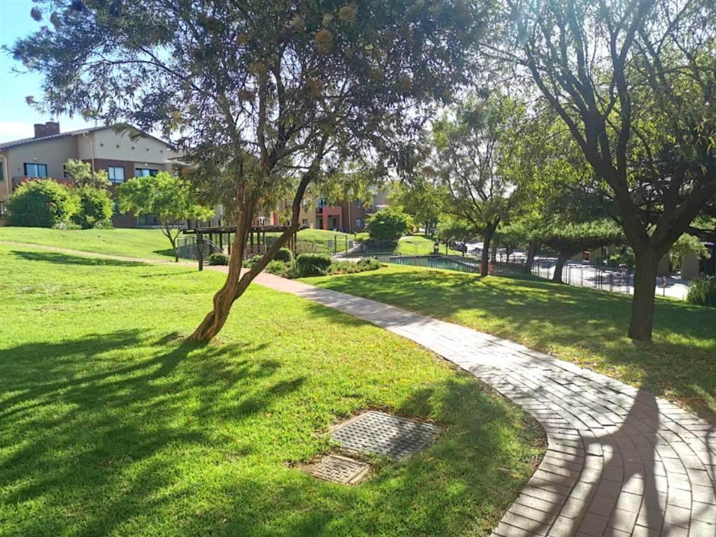uma passarela num parque com árvores e relva em Jackal Creek Golf Estate em Roodepoort