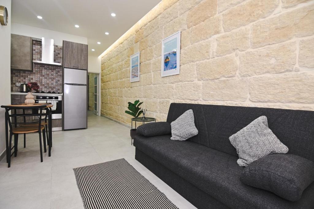 een woonkamer met een bank en een stenen muur bij Widnet il-Bahar in Marsalforn