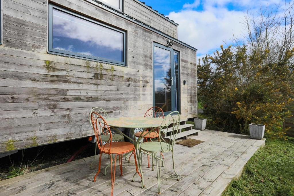 een tafel en stoelen op een terras naast een gebouw bij Très Jolie Tiny House Tout Confort in Prat