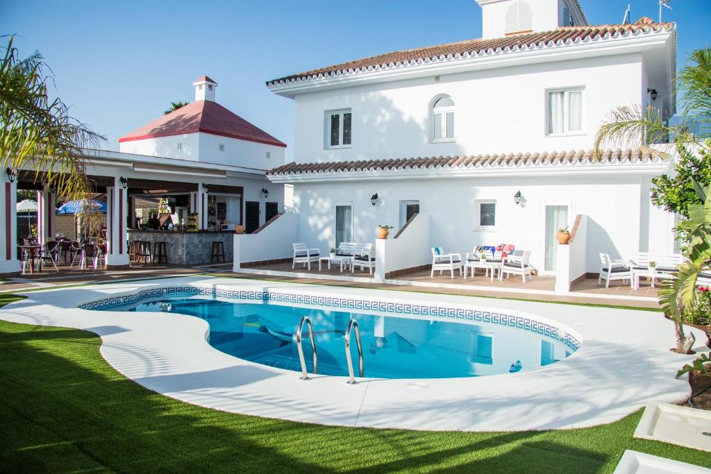 a villa with a swimming pool in front of a house at Hotel Novomar in Chiclana de la Frontera