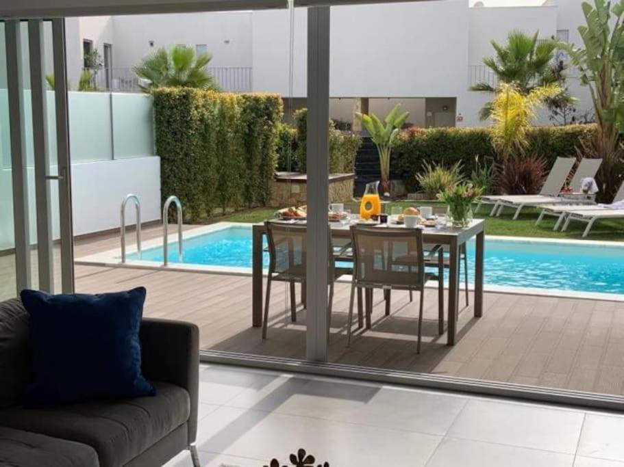 einen Essbereich mit einem Tisch und Stühlen neben einem Pool in der Unterkunft Luxury House - Privat Heated Pool & Ecologic & BBQ & Privacy & Albufeira in Albufeira