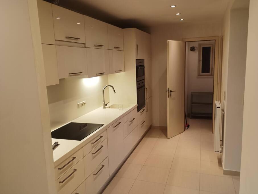 a white kitchen with white cabinets and a sink at Spacious modern 3 bedroom aparment in Prague