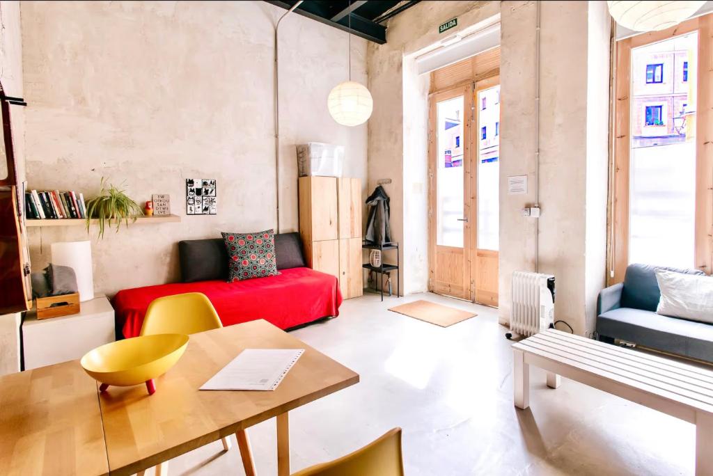 ein Wohnzimmer mit einem roten Sofa und einem Tisch in der Unterkunft Estudio Loft en el centro de Madrid reformado en enero 2024 in Madrid