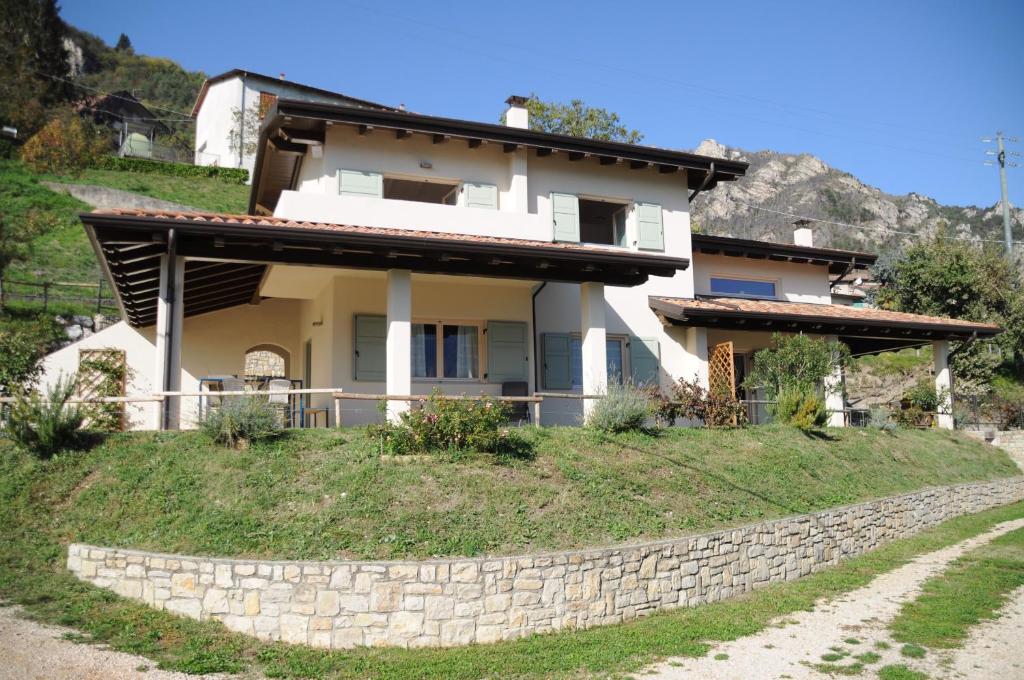 a house on a hill with a stone wall at Villetta 56 Blu Yellow and Red Lake view Garden Private Parking by Garda Domus Mea in Tremosine Sul Garda