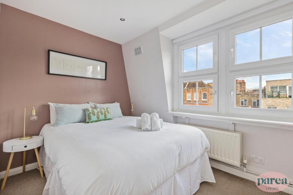 ロンドンにあるParea Living - Cute Cosy Flat near Shoreditch, Hackney, Hoxtonのベッドルーム1室(白いベッド1台、窓2つ付)