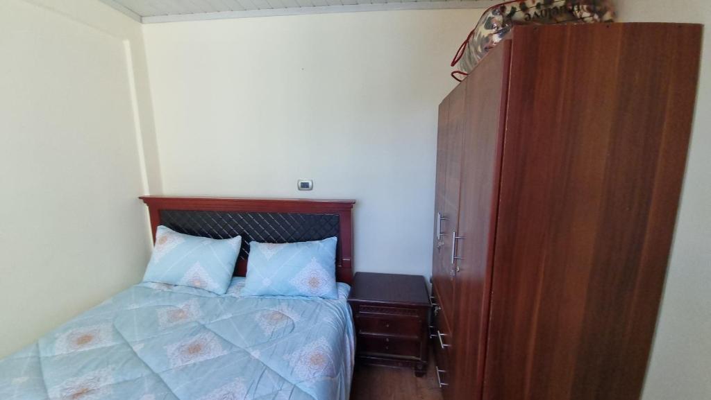 1 dormitorio con 1 cama y armario de madera en Getu furnished apartments at CMC, en Addis Ababa