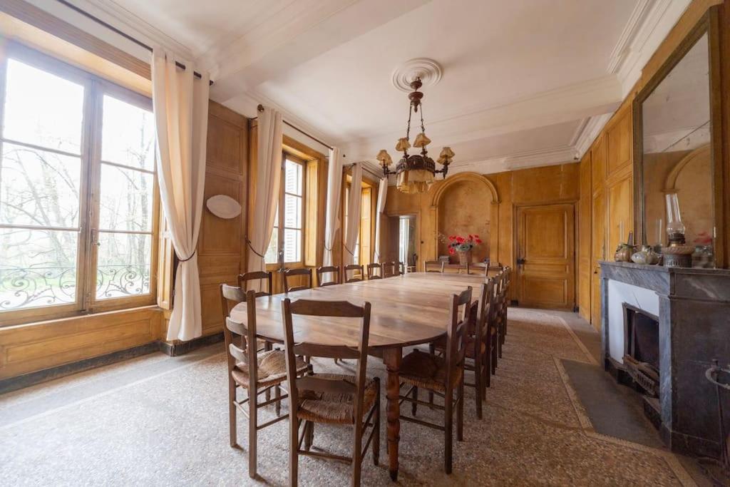 uma sala de jantar com uma grande mesa de madeira e cadeiras em Château Monvallon em Charentay