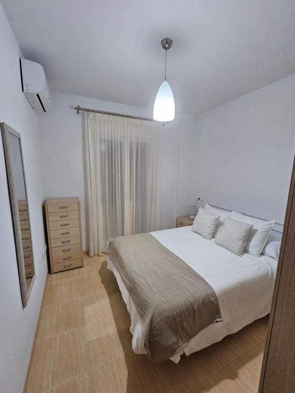 um quarto branco com uma cama e uma janela em Apartamento El Ingenio em Nerja