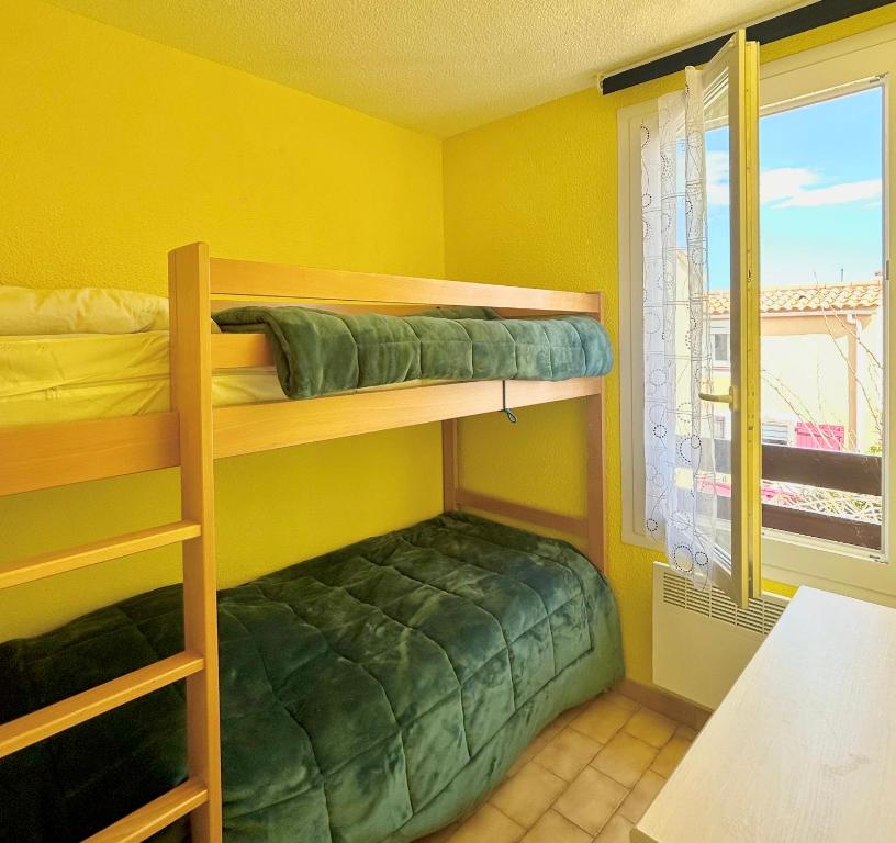 a bedroom with two bunk beds and a window at Maisonnette 6 personnes à 500 m de la plage Parking 6GOEL18 in Le Barcarès