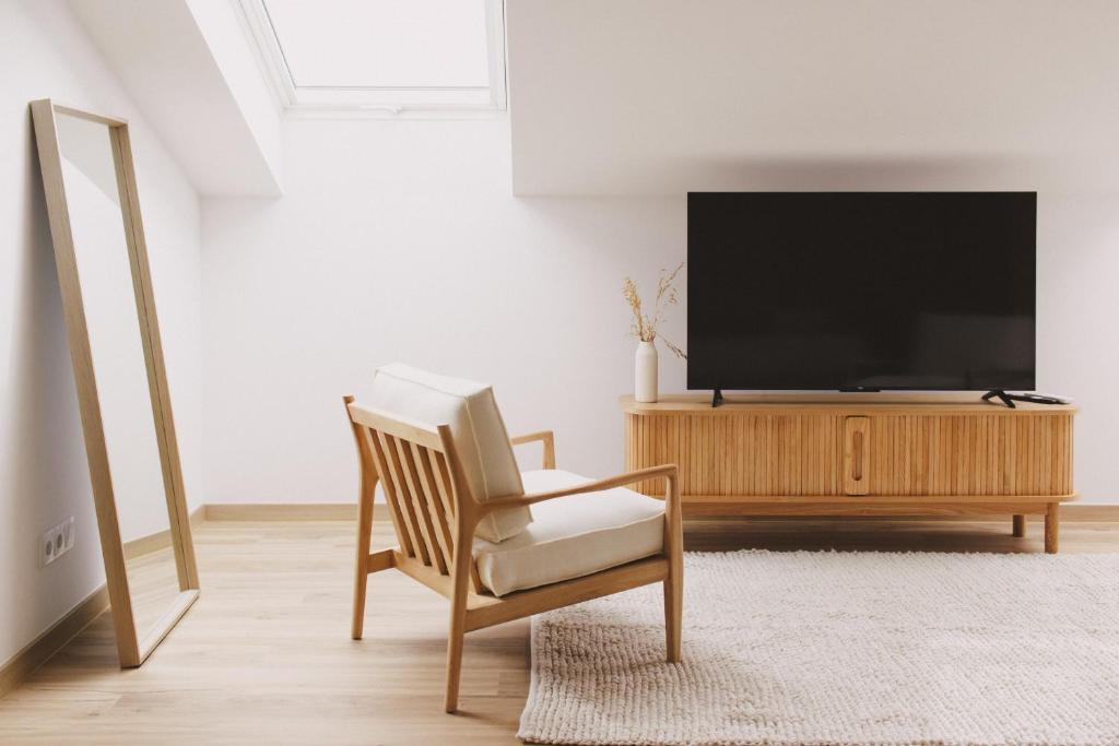 a living room with a chair and a flat screen tv at Pure Flor de Esteva in Vila do Bispo