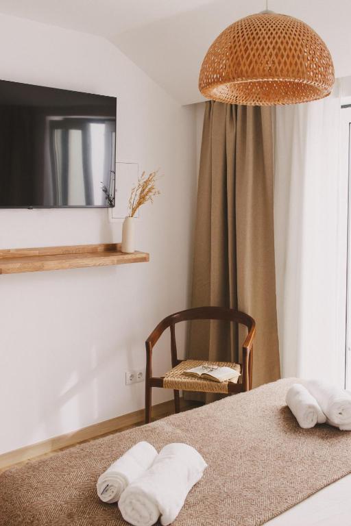 a bedroom with a bed and a chair and a television at Pure Flor de Esteva in Vila do Bispo