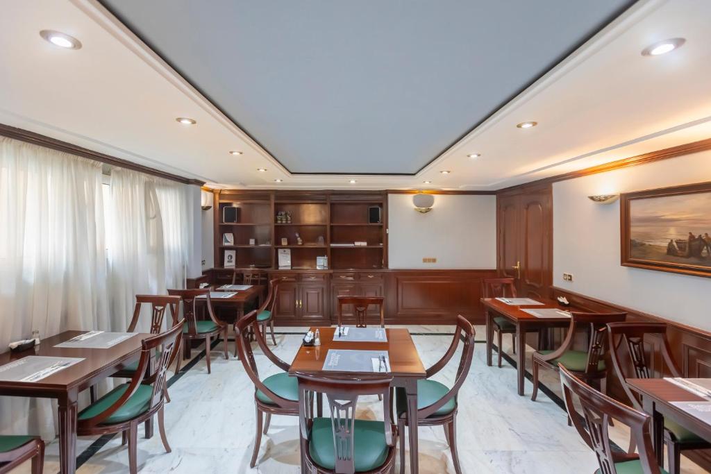 Un comedor con mesas y sillas de madera. en Soho Boutique Los Naranjos, en Málaga