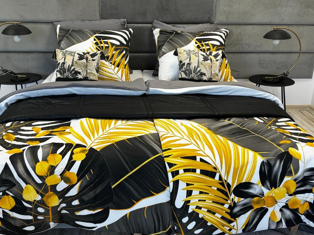 łóżko z czarno-żółtą kołdrą i poduszkami w obiekcie Apartamenty i pokoje „Pod Jedynką” w mieście Konstantynów Łódzki