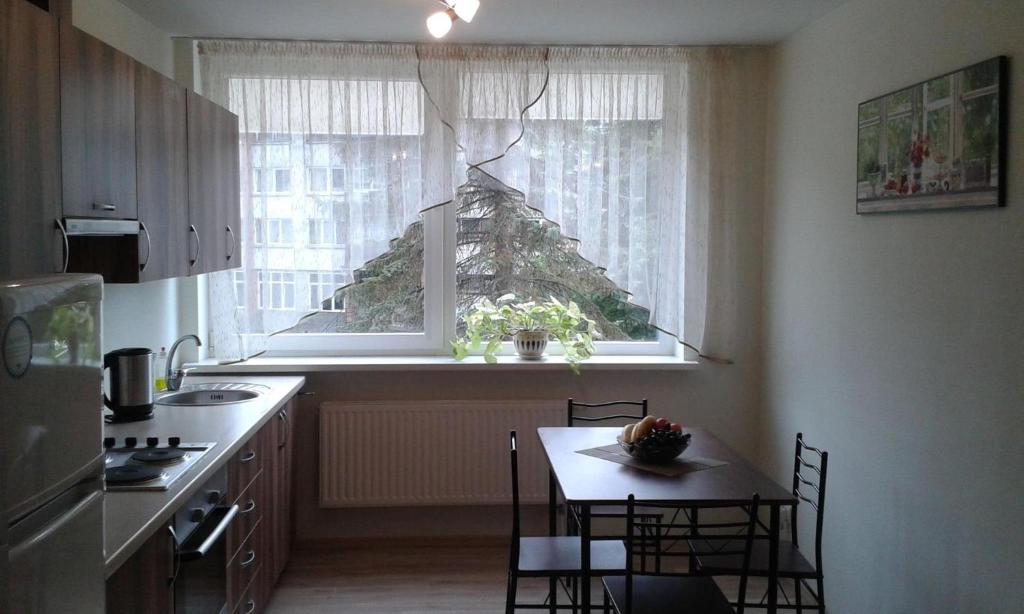 uma cozinha com uma mesa e uma janela com uma árvore de Natal em Butų nuoma Šilutėje em Silutė