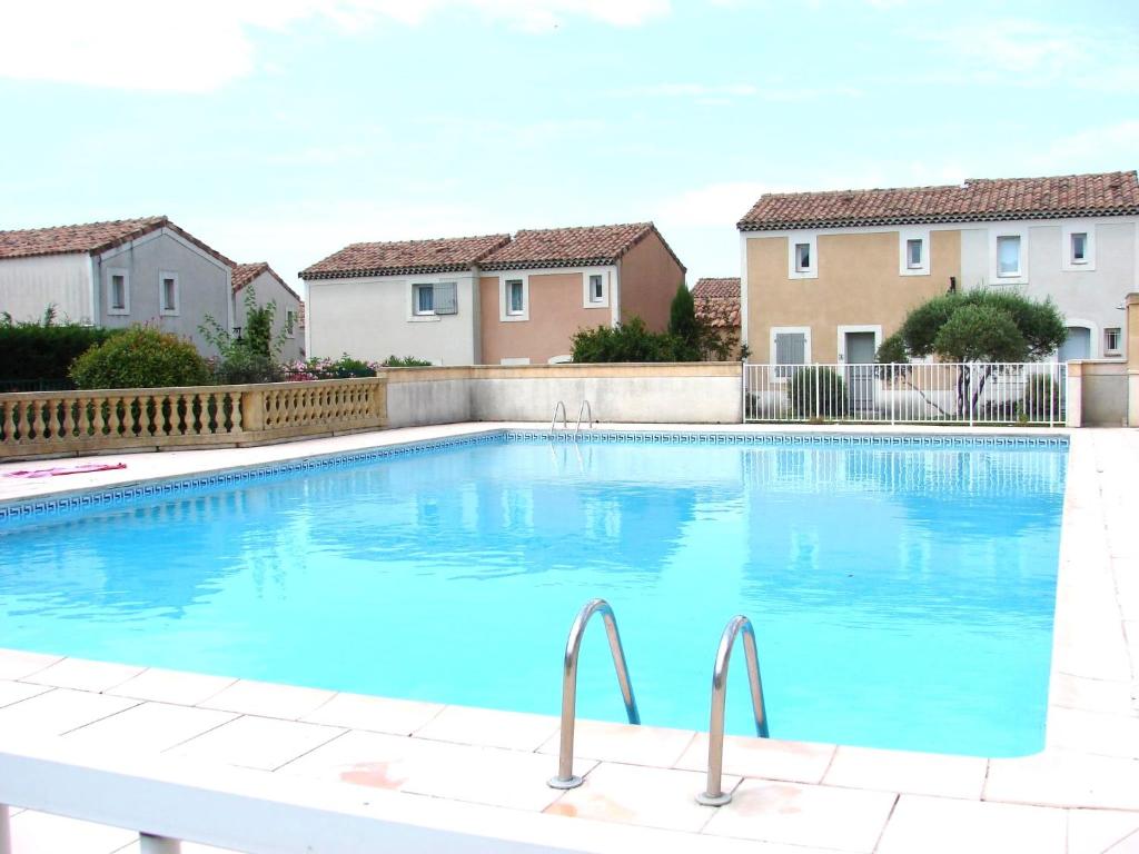 een groot blauw zwembad in een tuin met huizen bij Duplex dans résidence avec Piscine à Uzès in Uzès